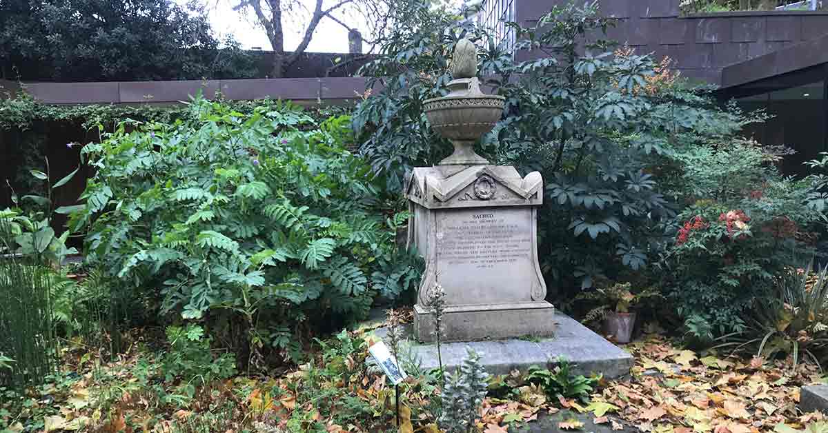 Foliage and a square stone sculpted memorial.