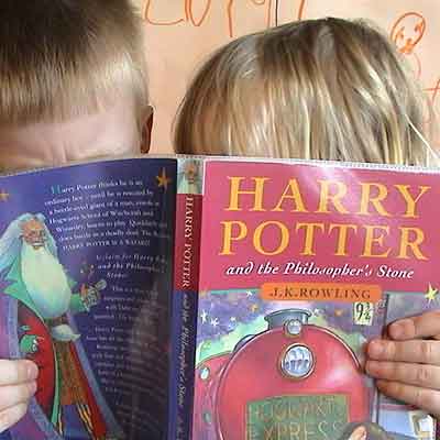 Children eagerly reading a Harry Potter book.