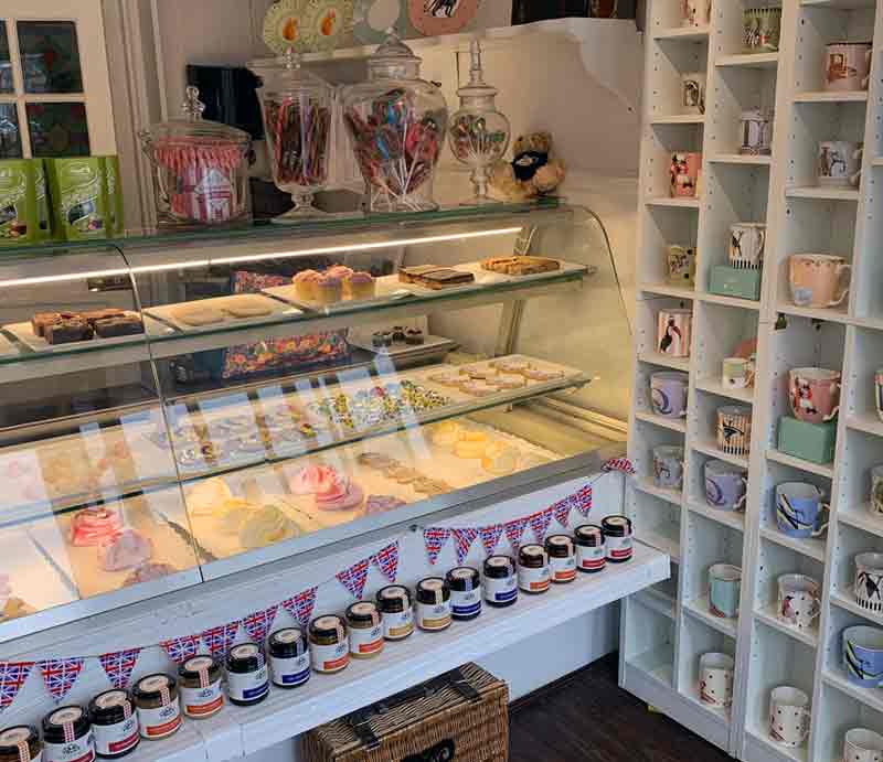Interior counter displaying fancy cakes by souvenir mug display.