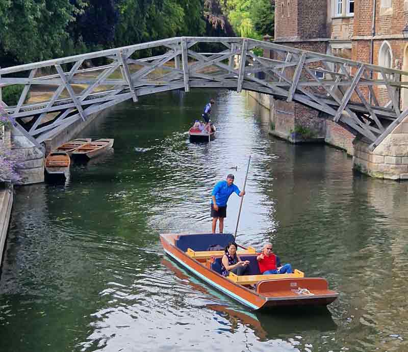 Puntsman in boat with timber bridge in background.