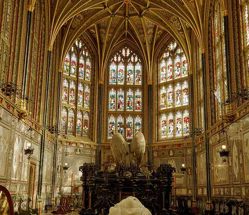 Ornate gilded Gothic interior with stained glass windows.