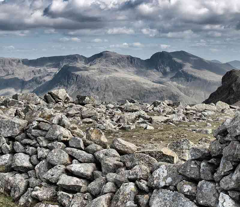 Stacked stones at the summit with mountains beyond.