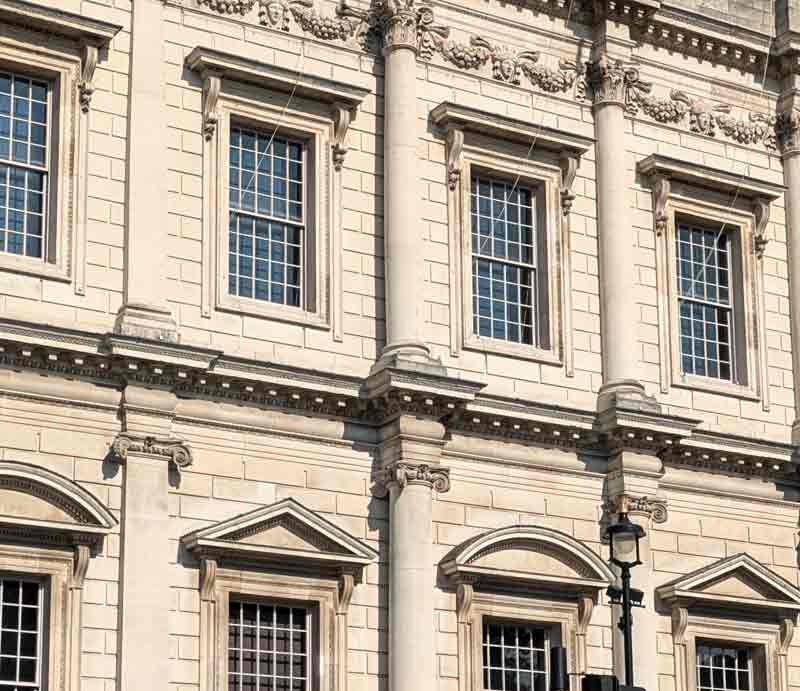 White stone exterior with columns and sash windows.