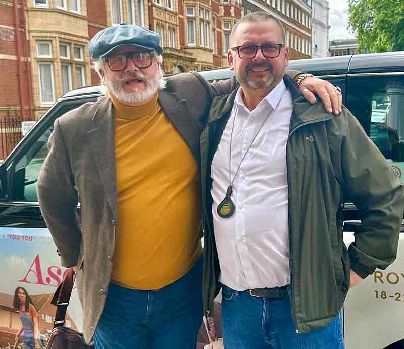 Guide and cabbie standing by the black taxi.