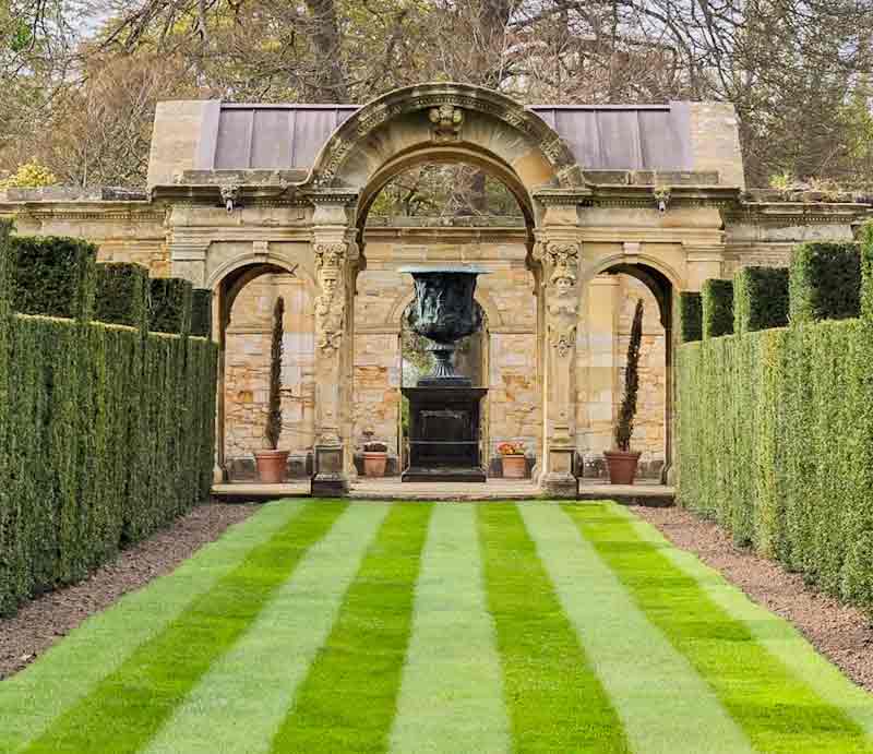 Stone arches, lawn and shaped hedges.