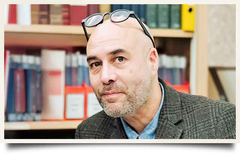 In a library with traditional green tweed jacket.