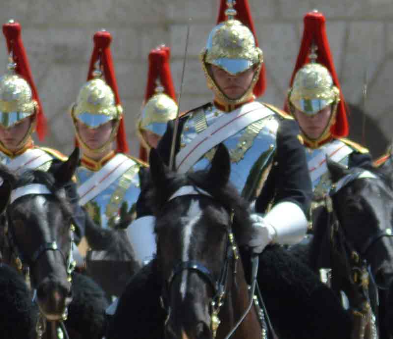 Mounted on horseback in full uniform.