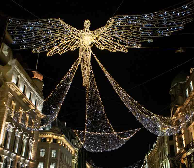 ‘The Spirits of Christmas’ angel with yellow illuminated buildings either side.