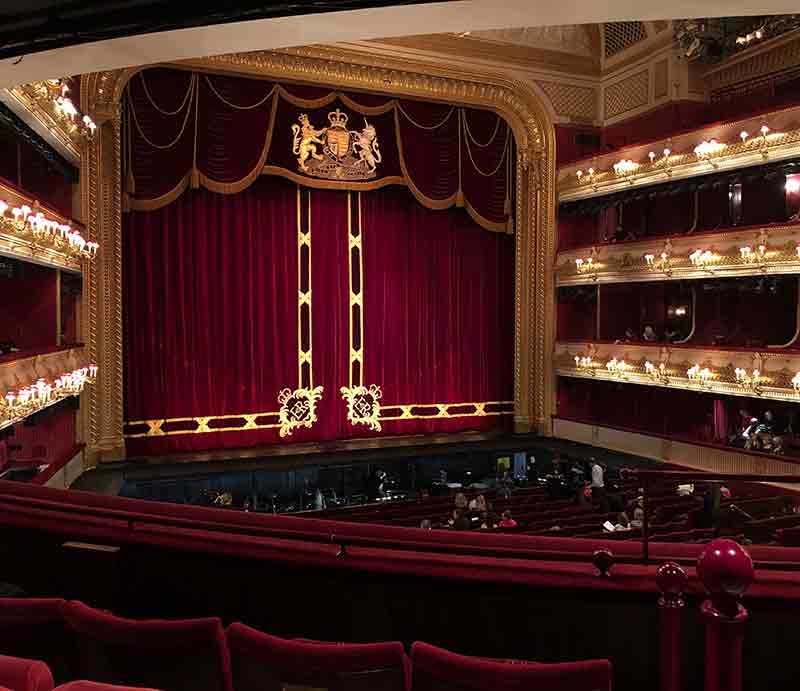 Interior facing stage with red curtain, stalls and boxes.