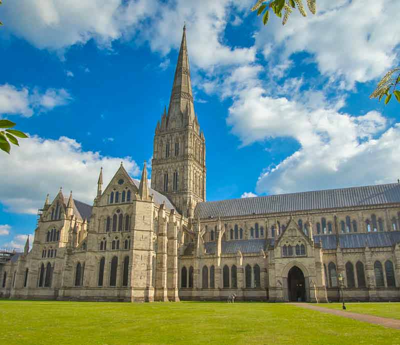 Salisbury Cathedral beneath a blue sky with light cloud.